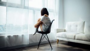 椅子の上で体育座りして孤独な女性